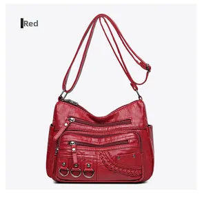 Dettaglio borsa rossa in pelle lavata con cerniere multiple e texture intrecciata