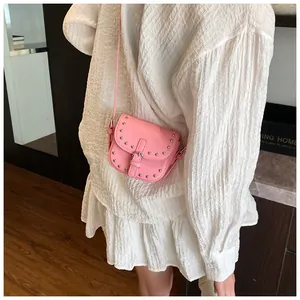 Detailed side view of pink mini saddle bag with silver rivets and metallic buckle strap