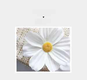Macro detail of hand-woven straw bag featuring a large white fabric daisy flower decor