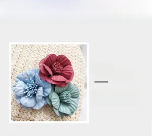 Detail of red blue and green camellia floral charms on a straw woven handbag