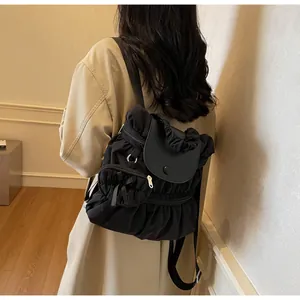 Close-up of black pleated nylon backpack with leather flap and magnetic closure detail