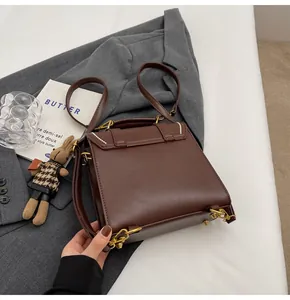 Detalle de bolso vintage marrón oscuro en cuero sintético con colgante de conejo y blazer