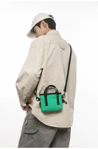 Detailed shot of green canvas crossbody bag with black handle and adjustable shoulder strap