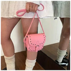 Close-up of pink mini saddle bag featuring silver stud trim and adjustable crossbody strap