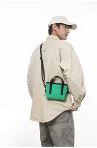 Mini green canvas tote bag shown on a model with black adjustable shoulder straps