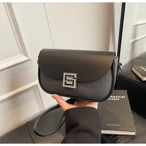 Detail of the black saddle bag showing mixed leather textures and a silver S-shaped buckle