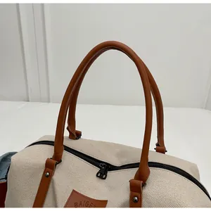 Detail of travel bag with beige canvas texture, brown leather trim and metal zipper