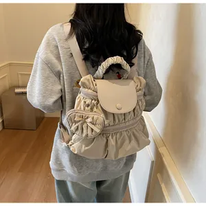 Detail of beige pleated nylon backpack with heart-shaped pendant and cloud-like top handle