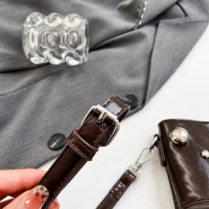 Detalle de correa ajustable de cuero brillante con hebilla plateada en un bolso marrón