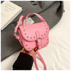 Close-up of pink mini saddle bag with silver studs and matte leather finish texture