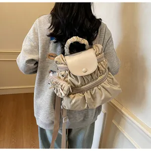 Detail view of beige pleated nylon backpack with matching mini coin purse attachment