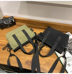 Mini nylon crossbody bags in olive green and black on a wooden table with accessories