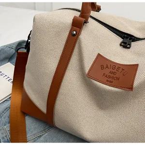 Detailed close-up of beige canvas travel bag with premium brown leather stitching and handles