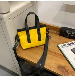 Detailed close-up of yellow nylon tote bag on wooden table with retro camera and magazine
