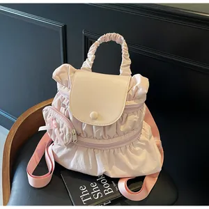 Close-up of pleated nylon backpack in pink with cream leather flap and bow charm