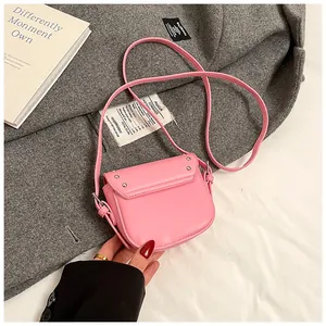 Detailed macro view of pink mini saddle bag featuring silver rivets on a grey coat