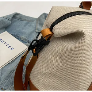 Detail of beige travel bag showing durable fabric, brown straps, and plastic buckle