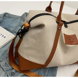 Detail of canvas travel bag with premium leather handles and brand logo patch