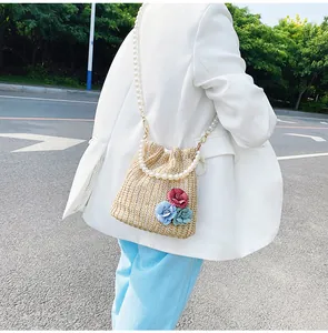 Close-up of straw bucket bag with pearl strap and colorful 3D floral accents