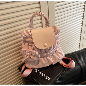 Detail of light pink nylon backpack featuring pleated fabric and bow ribbon charm