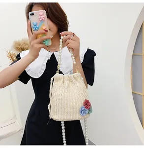 Detail of straw woven bucket bag with pearl chain handle and floral 3D appliques