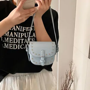Light blue mini saddle bag with silver rivets and buckle detail on leather shoulder strap