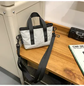 Detail of a beige quilted crossbody bag with black straps on a rustic wooden table