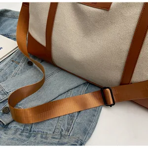Detail of canvas travel bag with leather trim and adjustable brown nylon shoulder strap