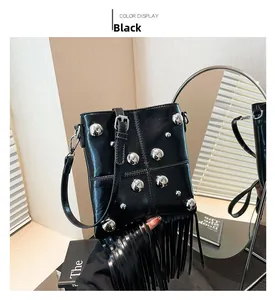 Detalle de bolso negro de cuero con remaches plateados y borlas largas de flecos