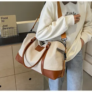 Side view of large beige canvas travel bag with brown leather trim and shoulder strap