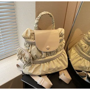 Detail of cream pleated nylon backpack featuring a cute bow charm and texture on books