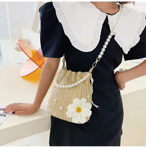 Detail of cream straw bucket bag featuring white pearl accents and a pearl bead strap