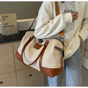 Canvas travel bag detail showing leather stitching and adjustable nylon shoulder strap