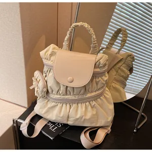 Detail view of beige pleated nylon backpack with flap closure and matching mini coin purse