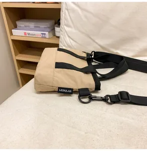 Detail view of khaki nylon crossbody bag with black handles and detachable shoulder strap