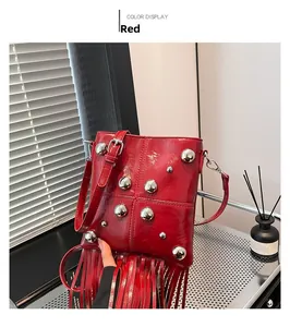 Detalle de bolso bandolera de charol rojo con remaches plateados y flecos largos sedosos