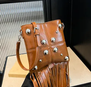 Detalle de bolso bandolera de cuero marrón con remaches plateados y flecos largos