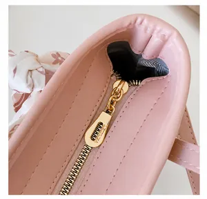 Detail der rosa Kunstledertasche mit goldenem Reißverschluss und gebundenem Seidentuch