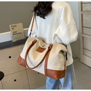 Detail of canvas travel bag with brown leather handles and adjustable shoulder strap