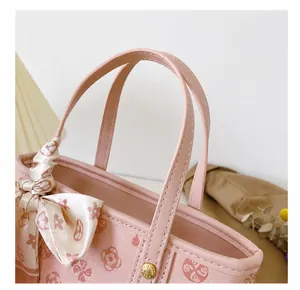 Detailaufnahme einer rosa Ledertasche mit floralem Seidentuch am Griff und edler Naht