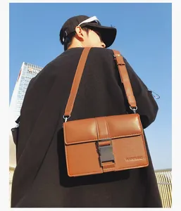 Detail of men's brown crossbody bag with silver buckle and leather grain texture