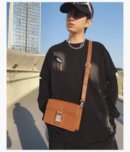 Close-up of brown faux leather messenger bag with silver buckle and street style design