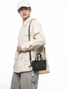 Minimalist black canvas crossbody phone bag for women shown as worn on a male model