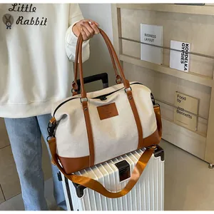 Detail of canvas travel bag with leather accents placed on a white suitcase