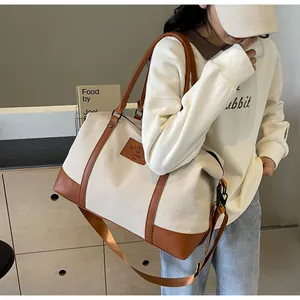 Close-up of canvas travel bag featuring brown leather trim and adjustable shoulder strap