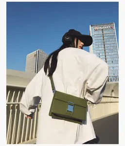 Detail of dark green flap crossbody bag featuring silver metallic buckle and logo