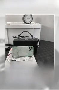 Capacity detail of black hard shell box bag showing it can hold a phone and power bank