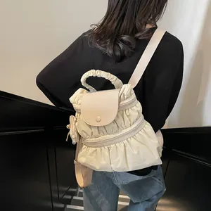 Minimalist cream nylon pleated backpack with matching side pouch shown on model