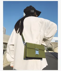 Detail shot of a matcha green square crossbody bag with silver buckle in outdoor setting