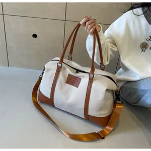 Detail of the cream canvas travel bag featuring brown leather handles and base reinforcement